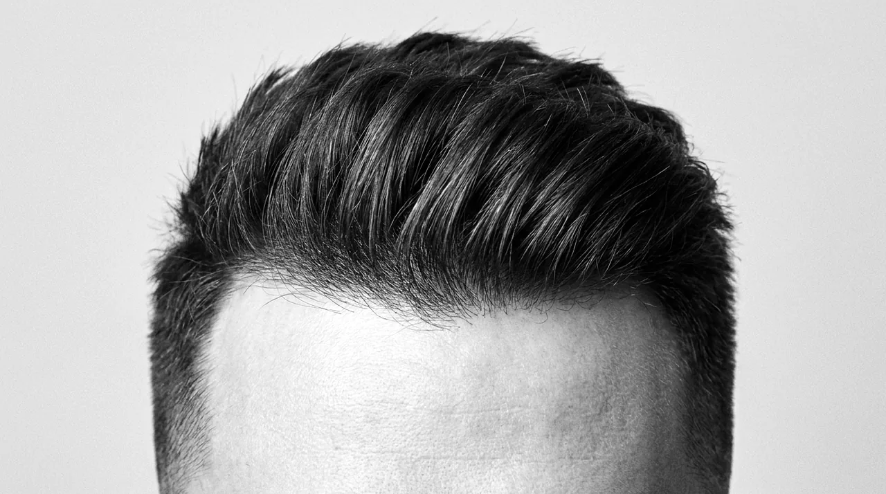 Photo nette d'une coupe homme vue de face, cadrée sur les cheveux : ligne du front et dessus texturé