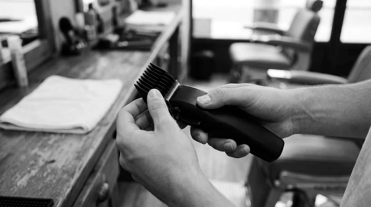 Mains enfonçant un sabot noir sur la lame d'une tondeuse sans marque, en gros plan