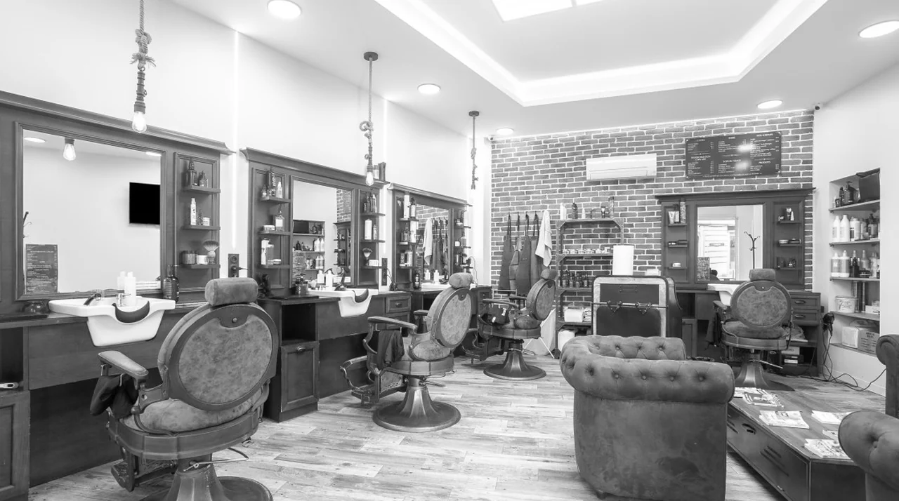 Intérieur du salon Lui Coiffeur de Draguignan : fauteuils de barbier, canapés club en cuir et mur de briques
